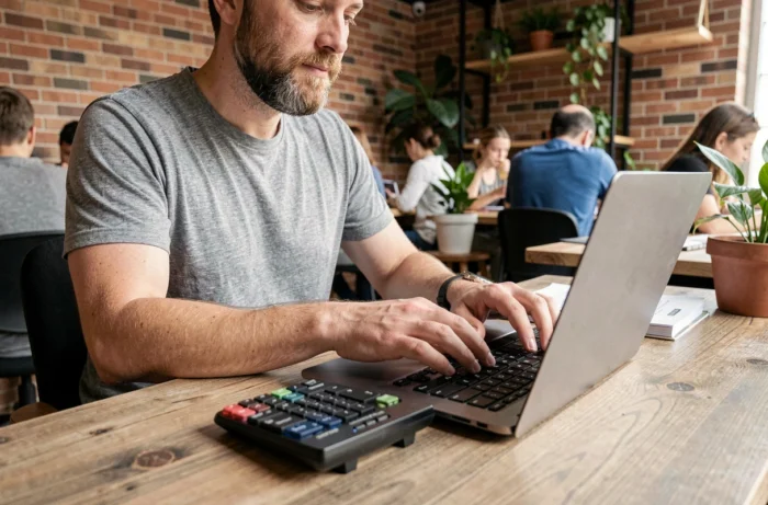 Homme appuyant sur la touche Home d'un clavier AZERTY externe dans un espace de coworking