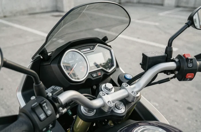 Gros plan sur le tableau de bord et le cockpit de la Honda CB500X lors d'une pause, avec compteur numérique et pare-brise réglable visibles